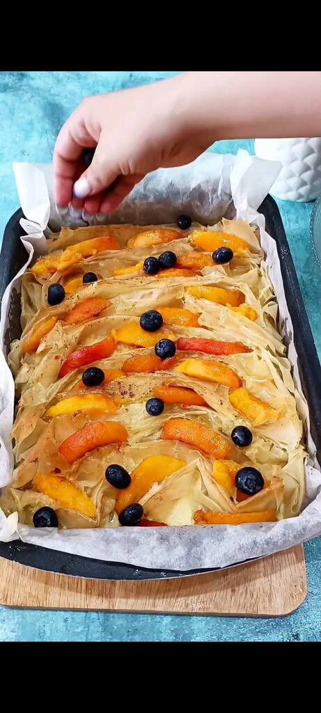 Pour the cream over the phyllo base and distribute peaches and blueberries