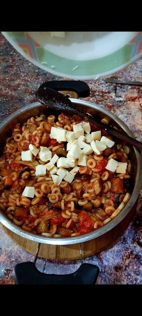 Season the pasta with tomato sauce and grated and diced cheeses