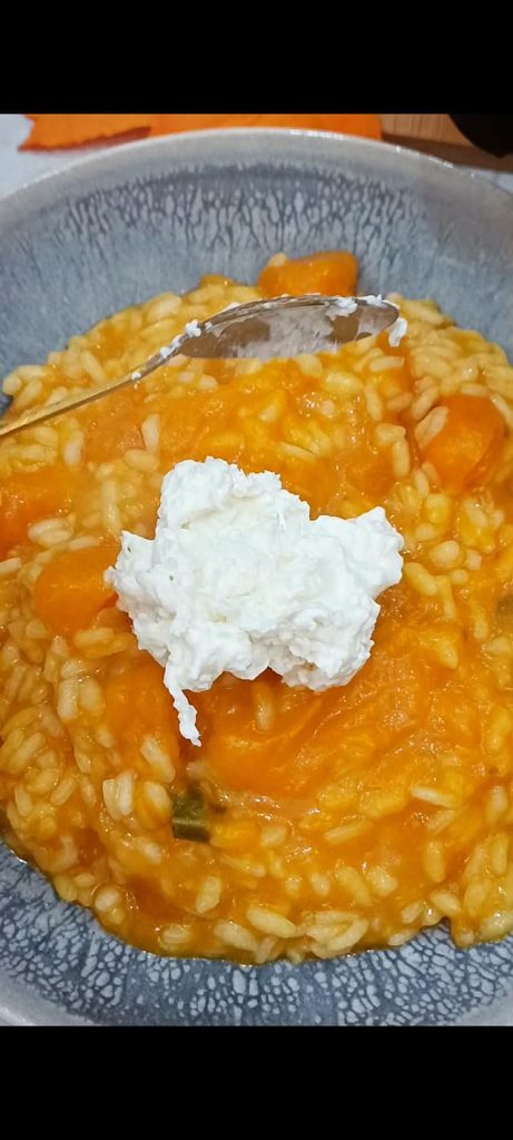 Plating the pumpkin risotto with stracciatella and hazelnuts