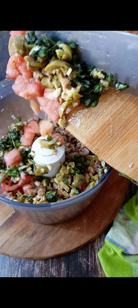 Mixing bread, tomatoes, chopped herbs, garlic, and olives
