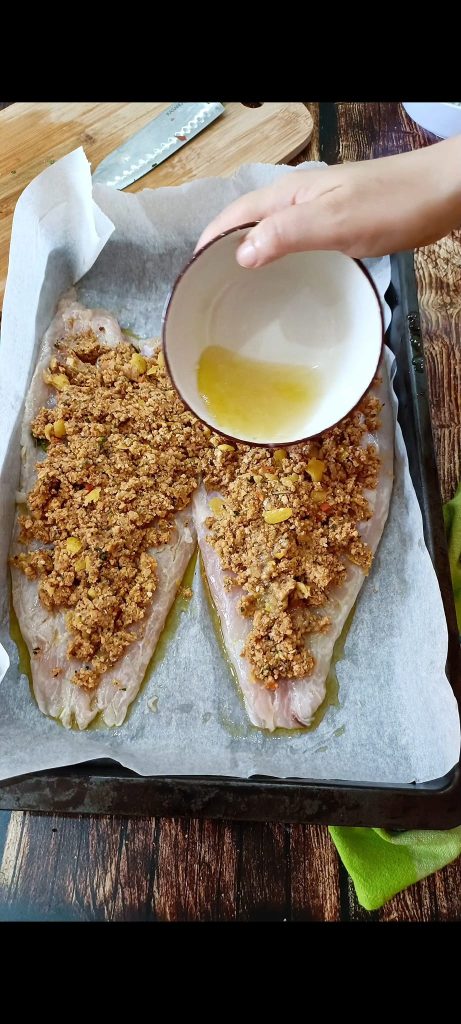 Spreading the breadcrumb over the fillets and drizzling with oil and lemon