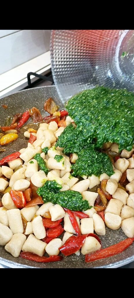 Pour the chickpea gnocchi into the pan with the peppers and add the arugula pesto