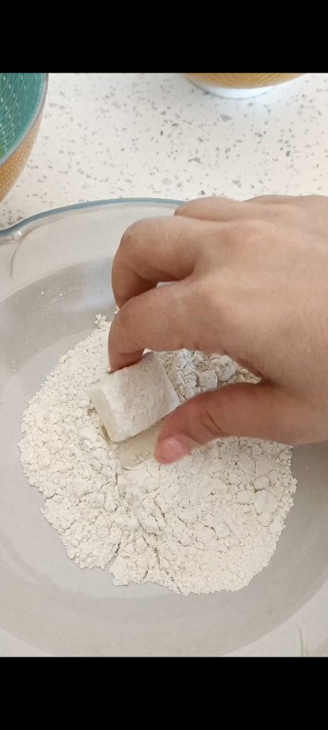 Coating each feta bite with flour