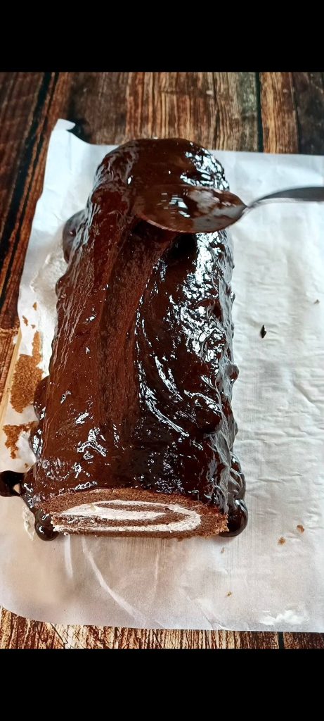We pour the chocolate ganache over the roll