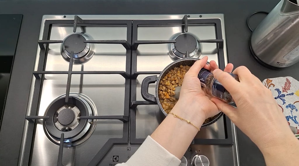 Adding pepper to stewed lentils