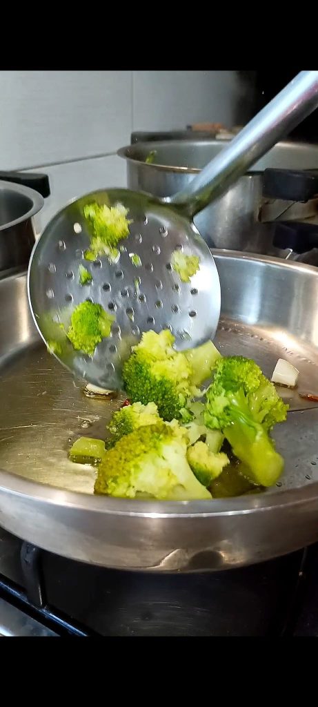 Broccoli sautéed in a pot with garlic, oil, and chili pepper