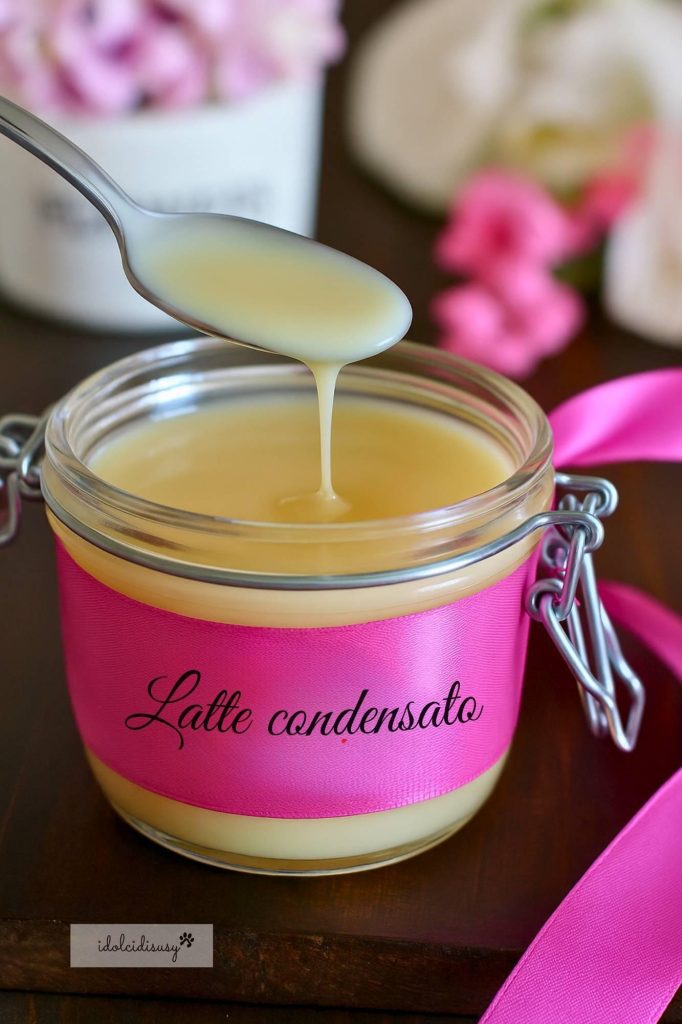 Homemade Condensed Milk dripping from a spoon into a jar decorated with pink ribbon – recipe also with Thermomix