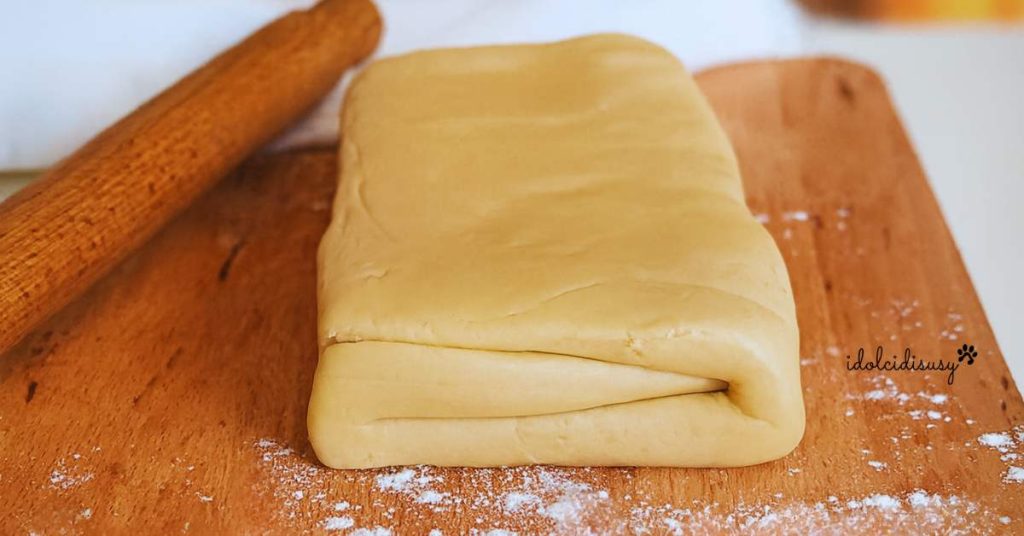 Homemade puff pastry block on floured cutting board with rolling pin