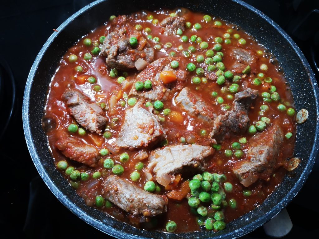 Stew with sauce and peas cooking in the pan