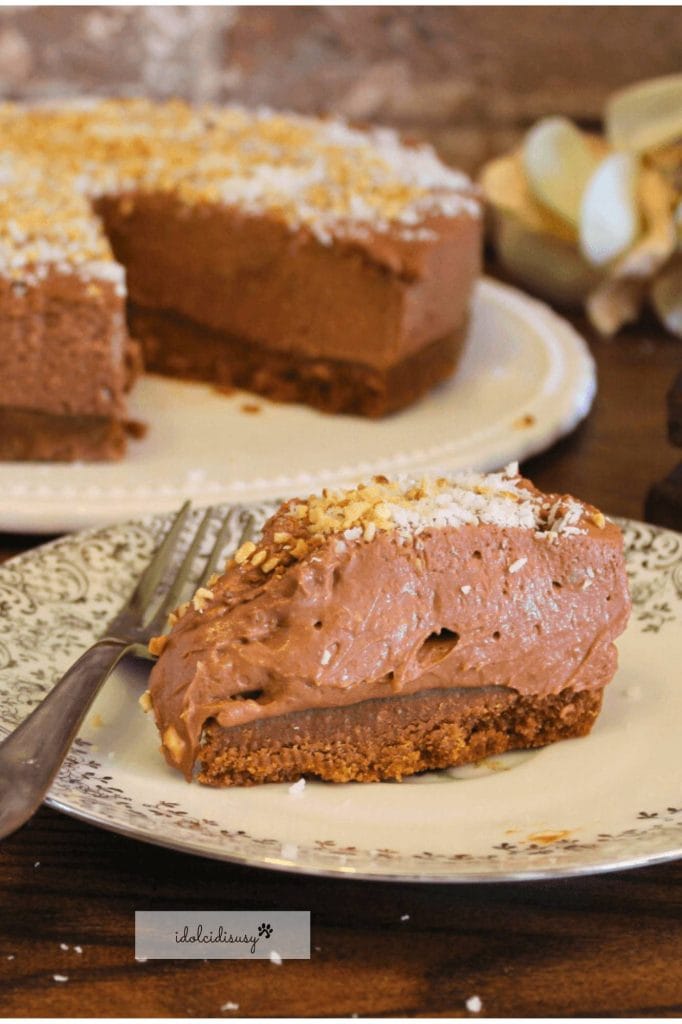 Slice of chocolate cheesecake with a cookie base and hazelnut crumbs on a decorated plate