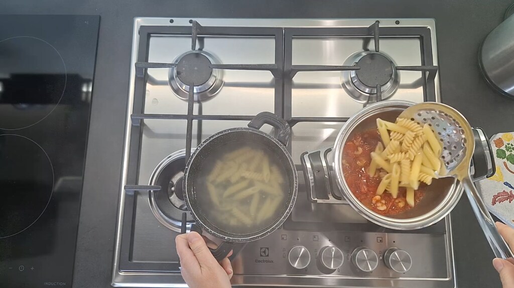 Pasta in the pot with sauce and frozen shrimp