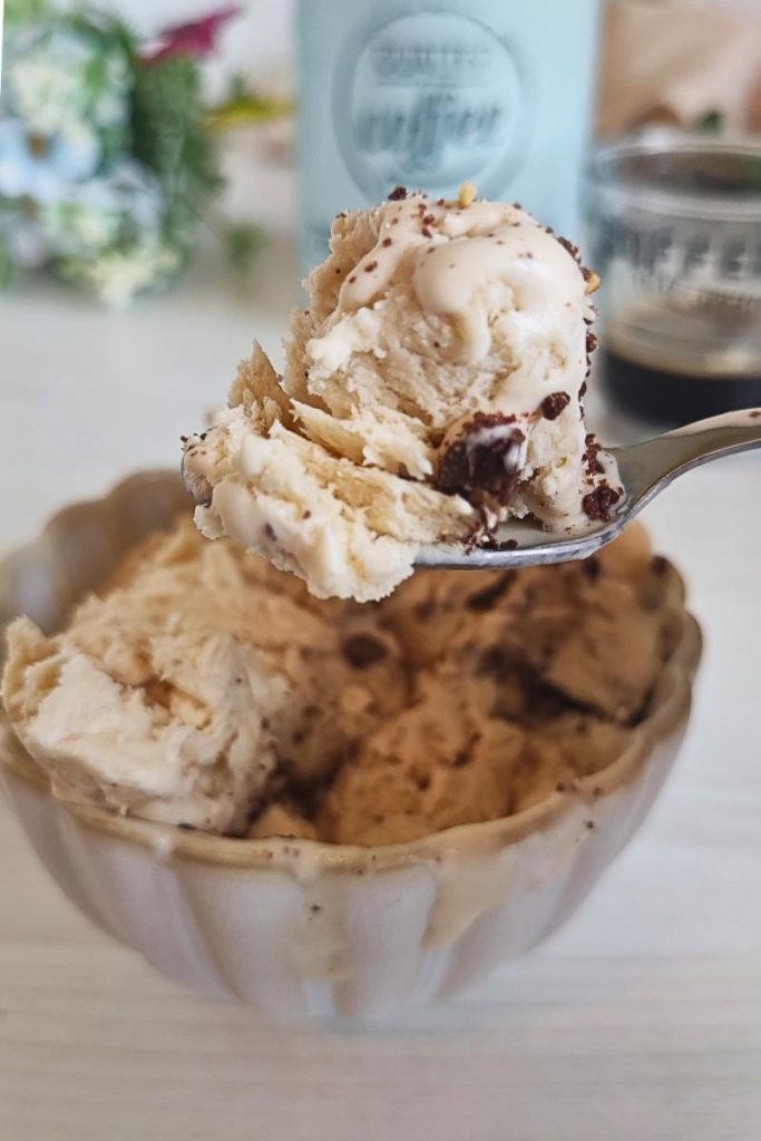 Detail of the creaminess of the coffee ice cream on a spoon, with blurred background and moka pot