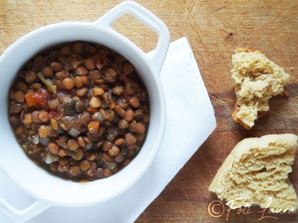 Stewed lentils in a white bowl accompanied by toasted bread