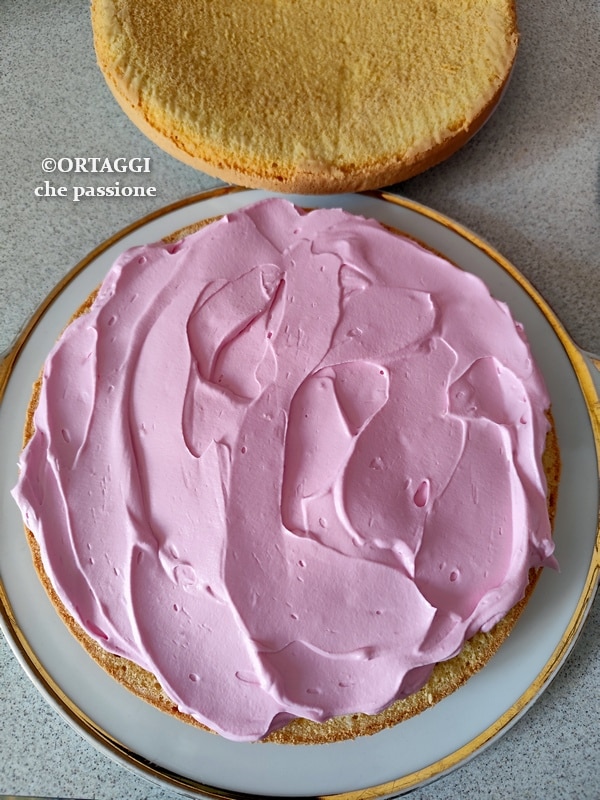 spread cream on pink strawberry cake
