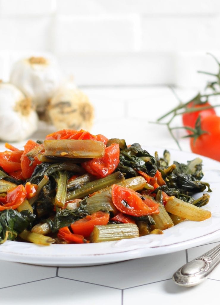 chard sautéed in a pan with garlic and cherry tomatoes