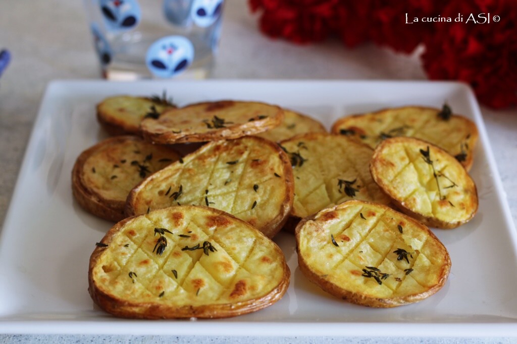 Sliced baked potatoes with garlic and fresh thyme, crispy and golden in a tray