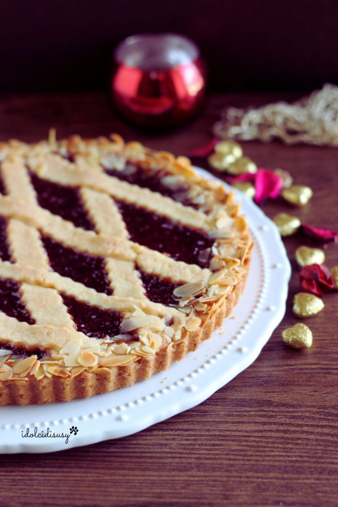 Homemade hazelnut Linzer torte with lattice decoration and almond border, served on white plate