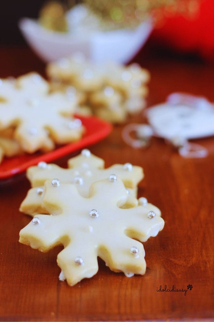 Detail of snowflake-shaped cookies with shiny glaze and silver sprinkles, perfect to give as gifts for Christmas