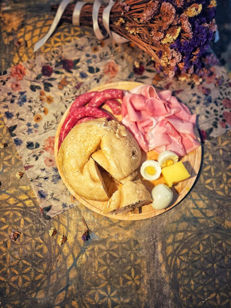 "Wooden board with Carinthian Osterjause: slices of sweet Reindling served along with slices of Osterschinken (Easter ham), boiled eggs, sausage, and butter