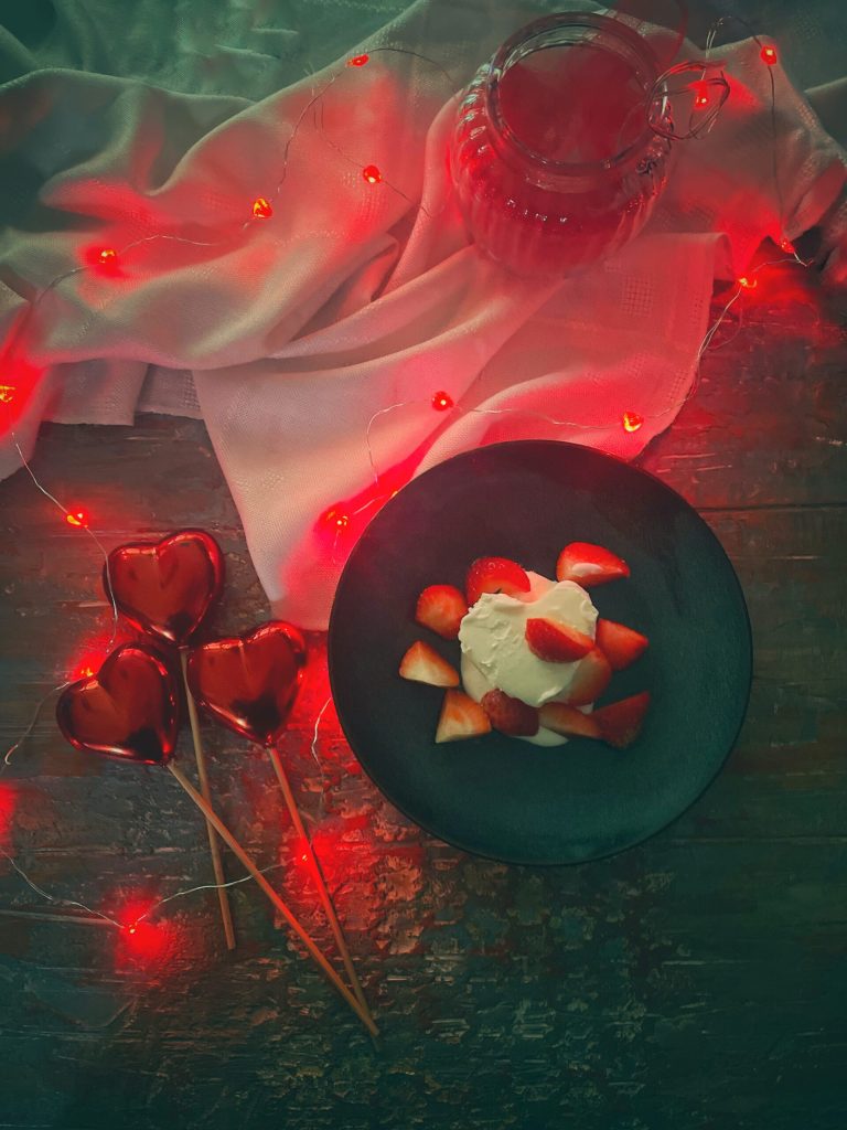 Coeur à la crème on black plate decorated with fresh strawberries, an elegant dessert for Valentine's Day.