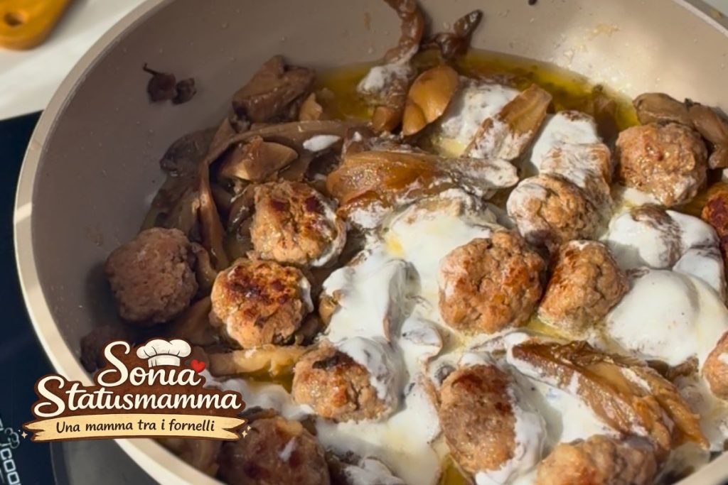Pouring the Greek yogurt and lemon cream over the meatballs in the pan with the heat off.