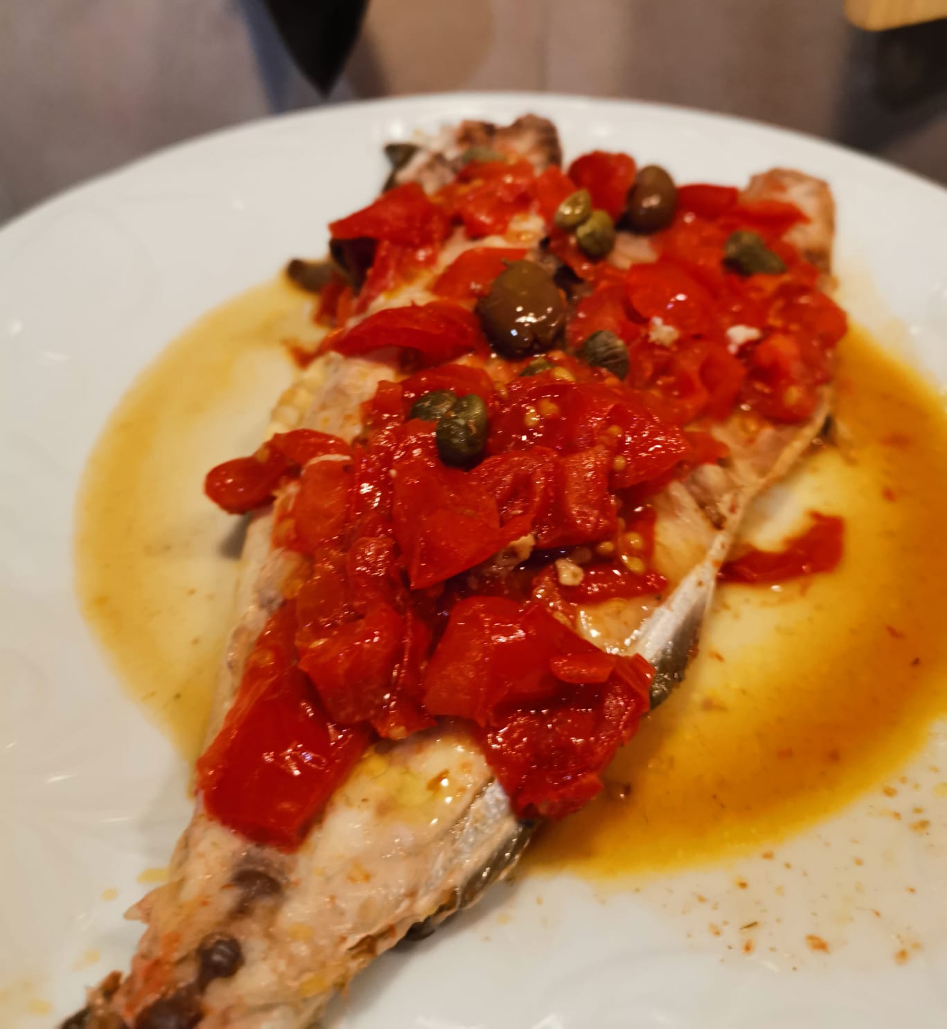 Amberjack in a skillet with cherry tomatoes, capers and Taggiasca olives