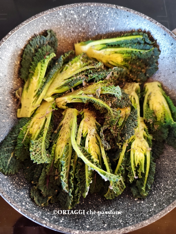 black kale shoots in skillet with aromatic herbs
