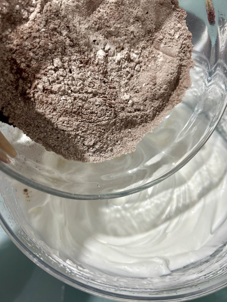 adding flour and cocoa to whipped egg whites for soft cake