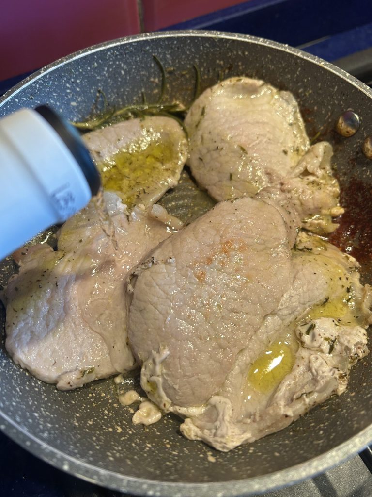 pork loin slices in the pan cooking with white wine