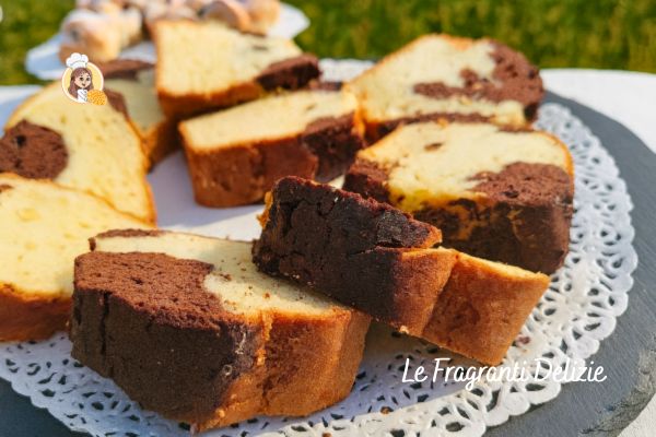 Thick slices of marble cake with well-defined vanilla and cocoa veins, laid on a lace doily in an outdoor setting.