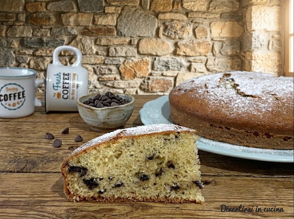 Slice of soft yogurt cake with chocolate chips on a wooden table, rustic stone background