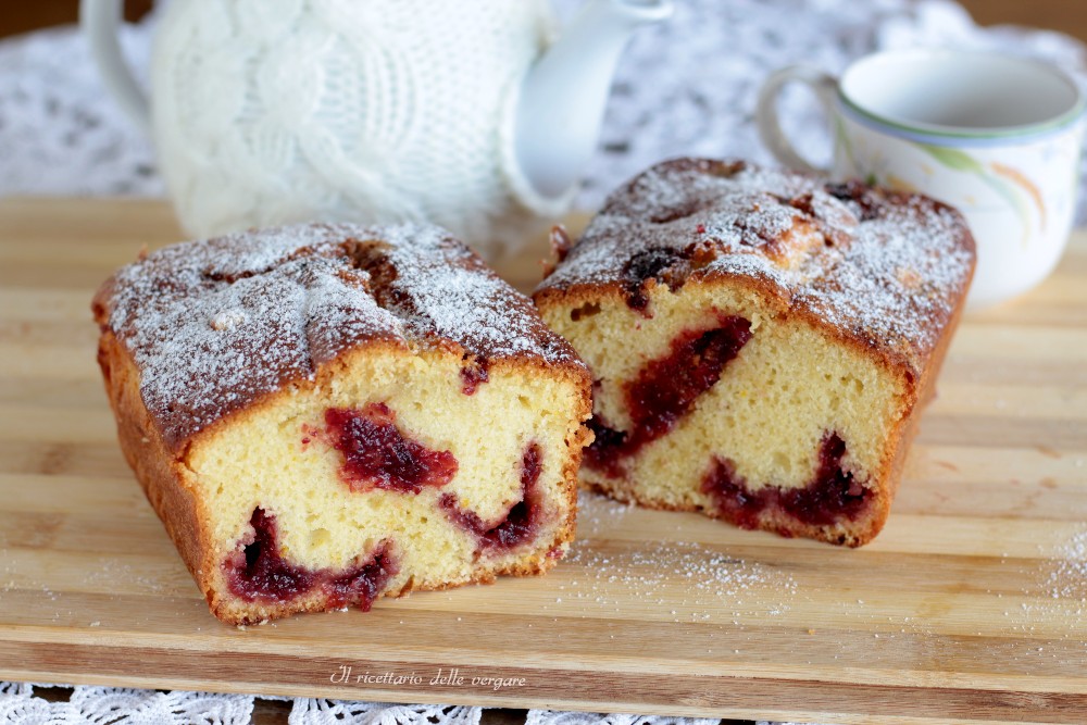 Two slices of cloud plumcake with a jam-filled center on a wooden cutting board dusted with powdered sugar