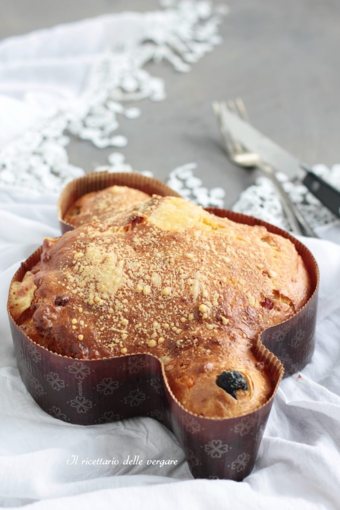 Vertical shot of a slice of savory colomba with soft crumb, filled with black olives and pieces of melted cheese
