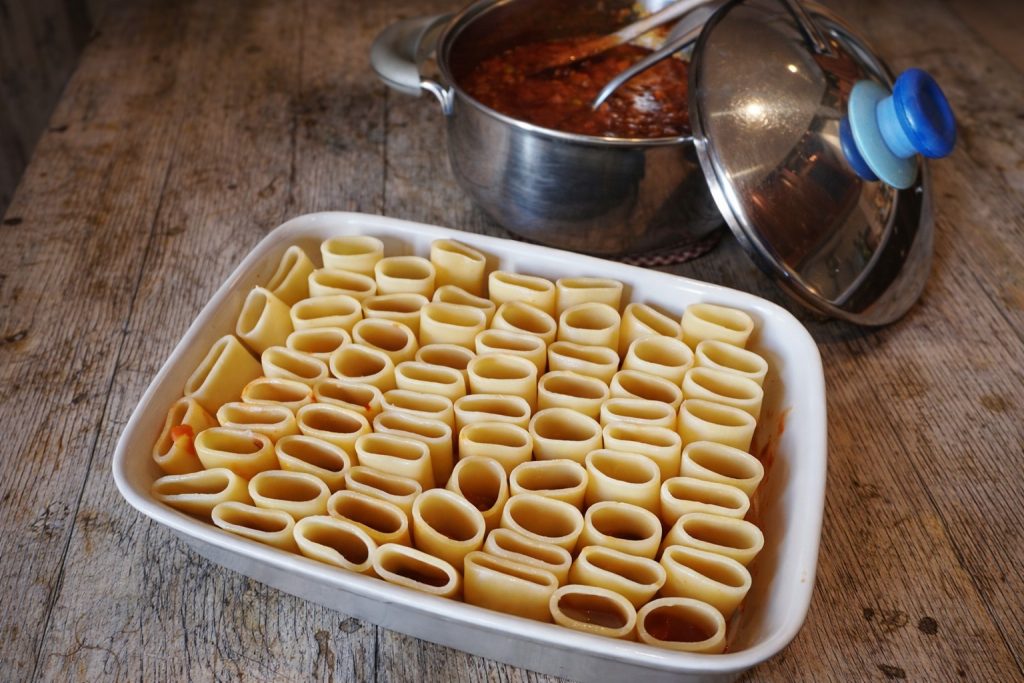 Raw paccheri arranged upright in a baking dish ready to be filled