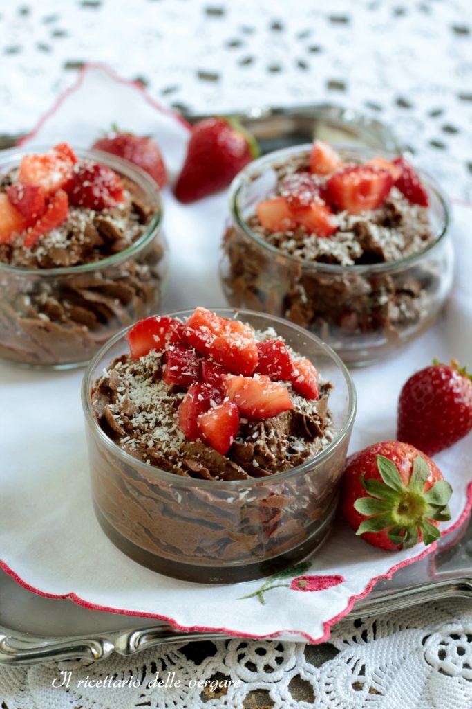 Top detail of three small bowls of chocolate and coconut mousse with fresh strawberries