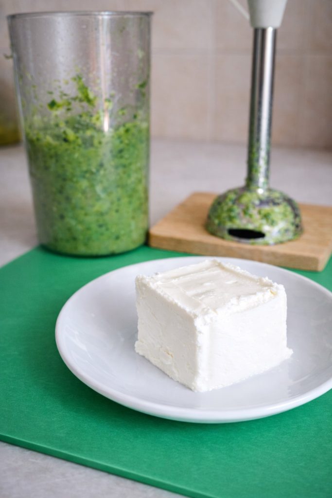 Robiola on a white plate with blended zucchini cream in the background