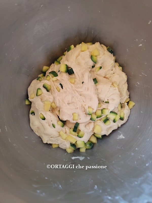 Teig der Focaccia mit Zucchini und Zwiebeln gleichmäßig machen