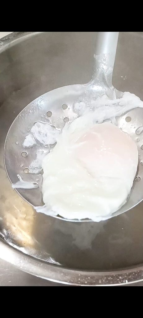Pochierte Eier auf einem Schaumlöffel