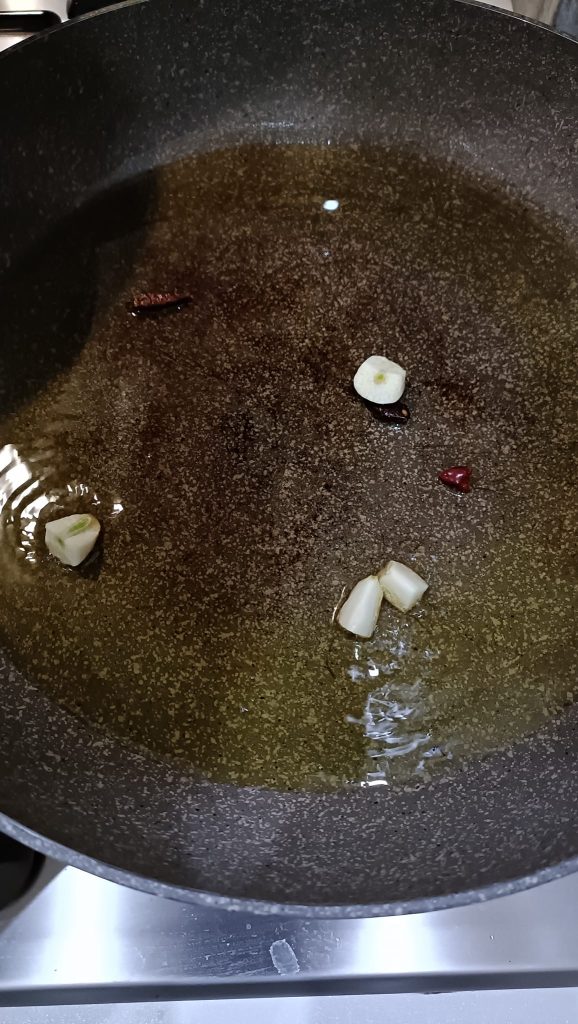 Öl, Knoblauch und Peperoni in der Pfanne