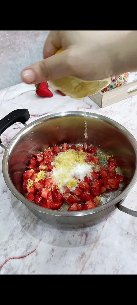 Erdbeeren mit Zucker, Schale und Zitronensaft in Topf