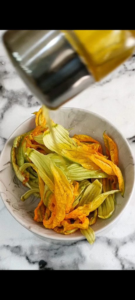 Wir würzen die Zucchiniblüten mit Öl, Salz und Pfeffer