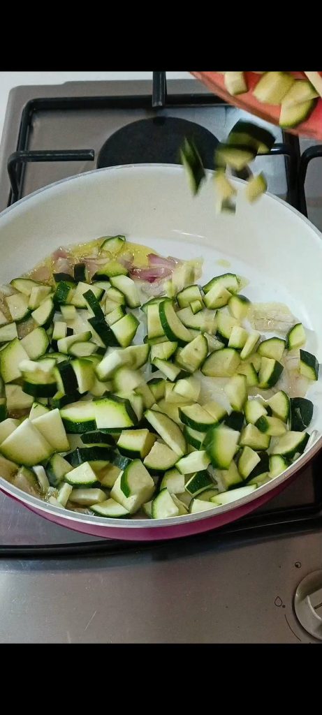 Wir braten die Zucchini mit Öl und gehackter Schalotte an