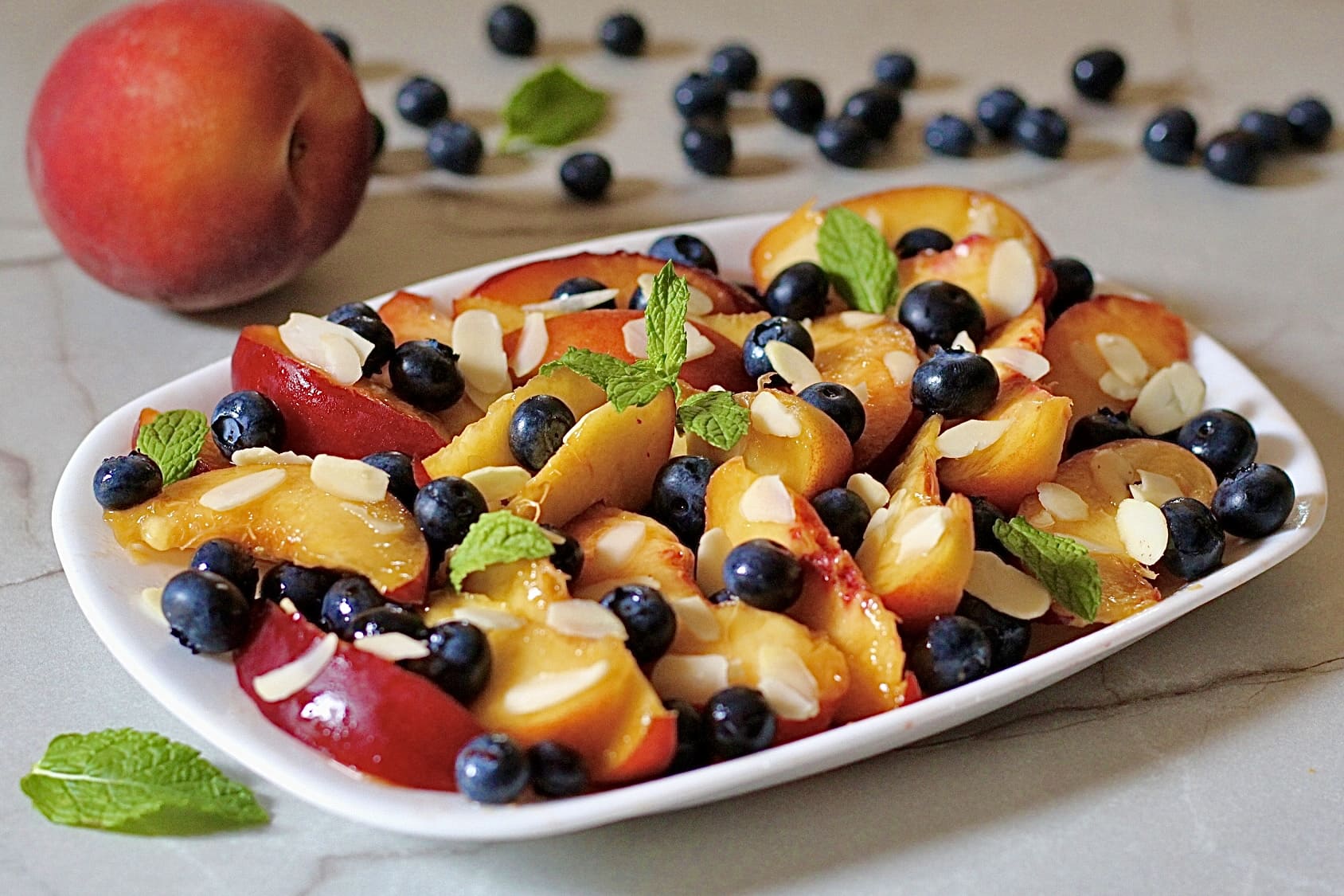 Obstsalat mit Pfirsichen und Heidelbeeren, mariniert mit Limette und Minze