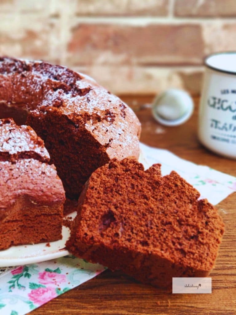Ein Stück fluffiger, weicher Schokoladenkuchen Bimby im Vordergrund, mit Puderzucker bestäubt