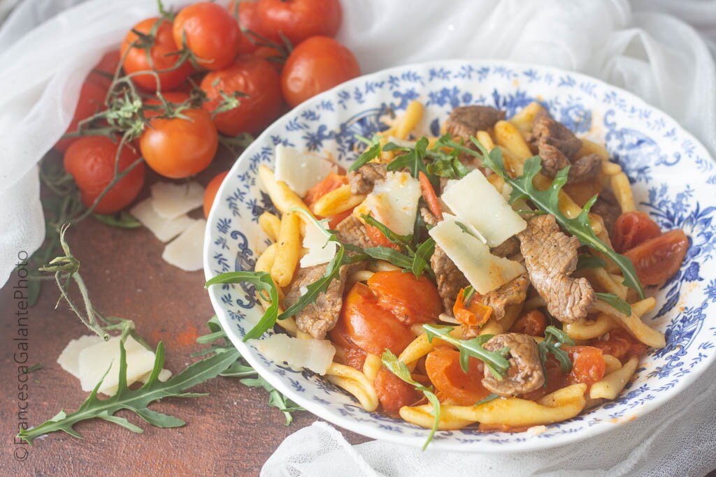 Frische Pasta mit Streifen von Kirschtomaten, Rucola und Grana