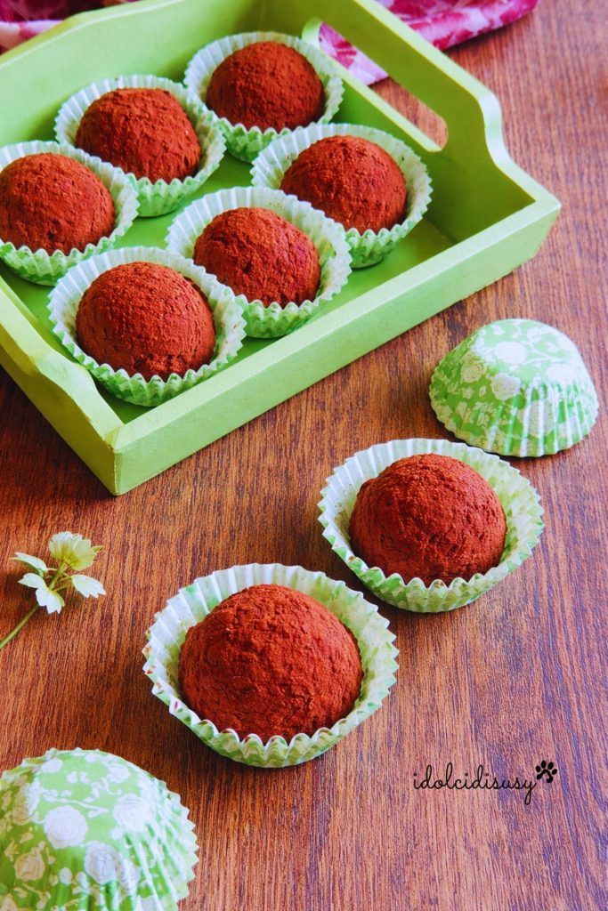 Hausgemachte Kakaotruffel auf einem grünen Tablett angeordnet, ungebackene Schokoladendesserts