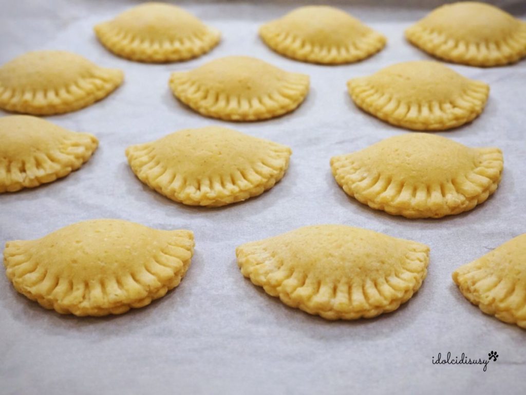 Halbmondförmige San-Giuseppe-Ravioli auf einem mit Backpapier ausgelegten Blech, bereit zum Backen