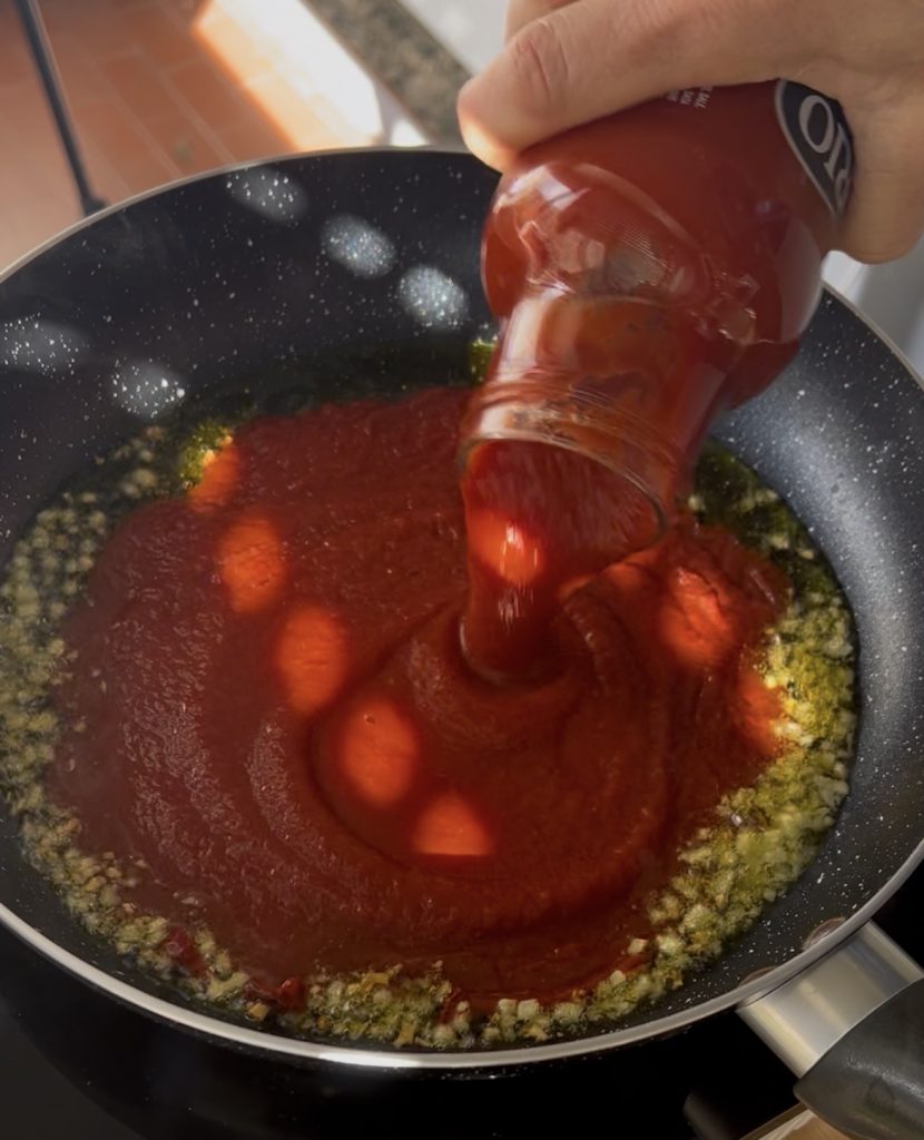 Vorbereitung von Spaghetti all'Assassina mit Tomatensauce in der Pfanne