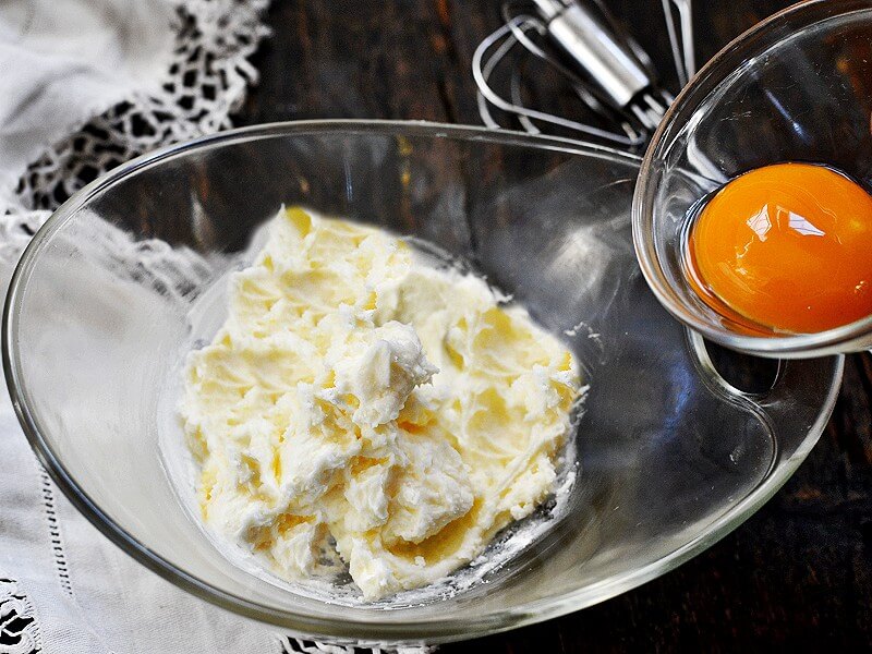 Schüssel mit weicher Butter und Puderzucker, dazu Eigelb