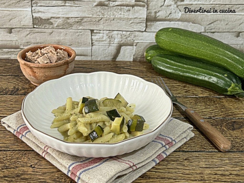 Nahaufnahme einer Schüssel mit cremiger Pasta, grünen Zucchini und Thunfisch, im Hintergrund ganze frische Zucchini und eine kleine Schale mit Thunfisch